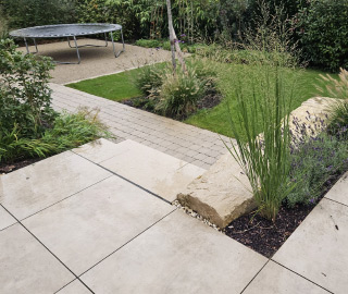Terrasse mit Natursteinplatten und klar geführten Gartenwegen.