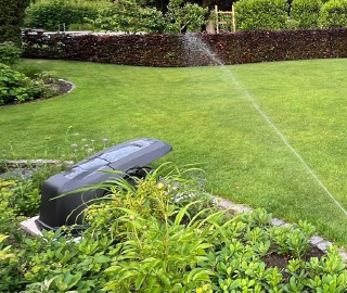 Automatische Bewässerung eines gepflegten Rasens in einer professionell angelegten Gartenanlage.