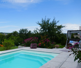 Moderner Gartenpool mit Terrasse und hochwertiger Bepflanzung in stilvoller Gartengestaltung.