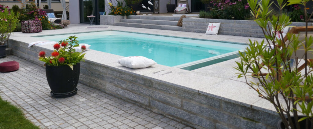 Moderne Poolanlage mit großzügiger Terrasse und stilvoll gestaltetem Garten.