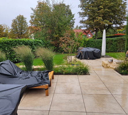 Moderne Gartenterrasse mit großformatigen Keramikplatten und gemütlichem Loungebereich.