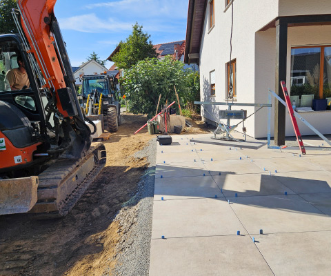 Terrassenbau mit großformatigen Platten während der Verlegung auf vorbereitetem Untergrund im Garten.