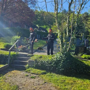 Mitarbeiter bei der Pflege einer bepflanzten Friedhofsanlage.