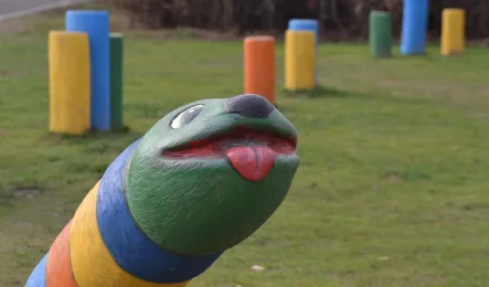Bunte Spielschlange auf einer Grünfläche mit farbigen Spielelementen.