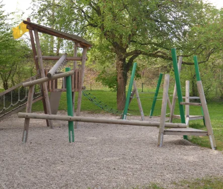 Kletter- und Balancieranlage aus Holz auf einem Spielplatz.