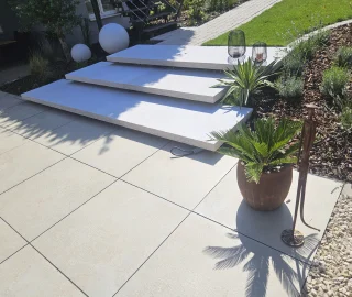 Helle Terrassenplatten mit breiten Stufen in einer modernen Gartenanlage.